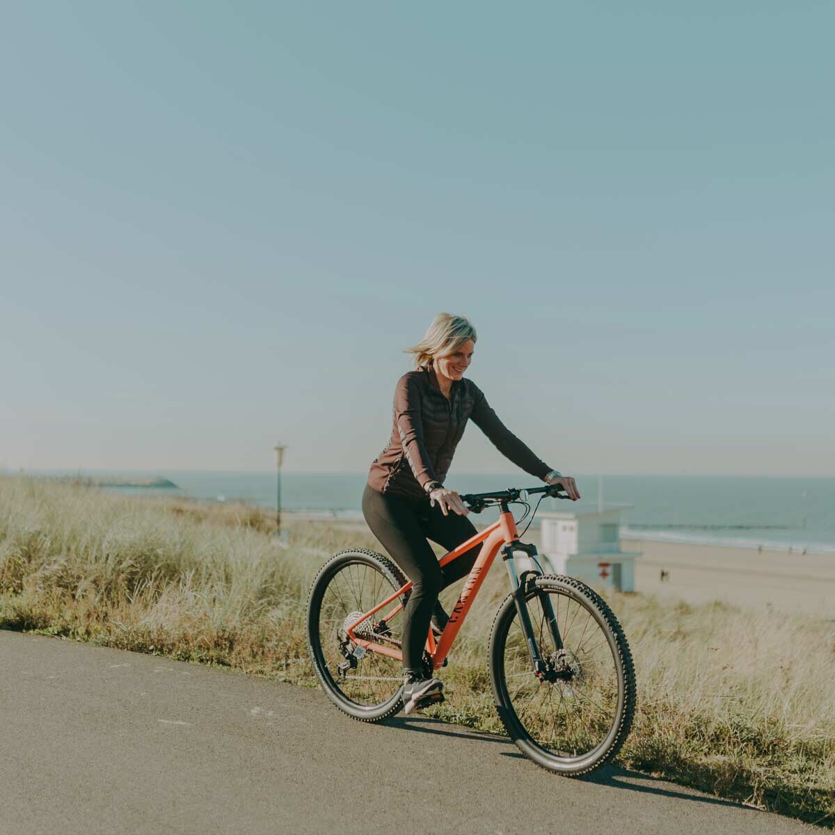 Woman cycling on the bike path along the dunes of the Zeeland coast.