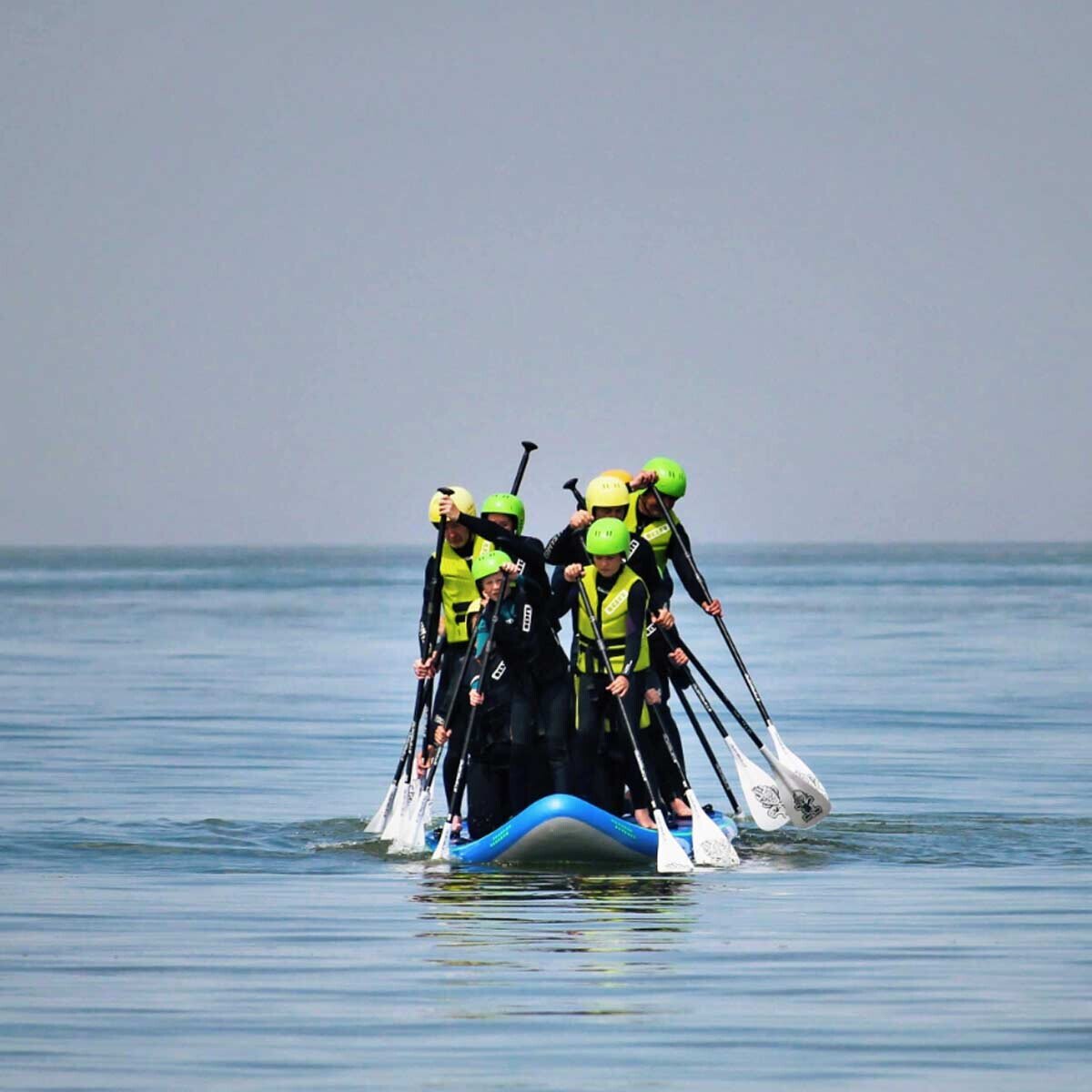 Group paddling together on a giant SUP board in the North Sea.