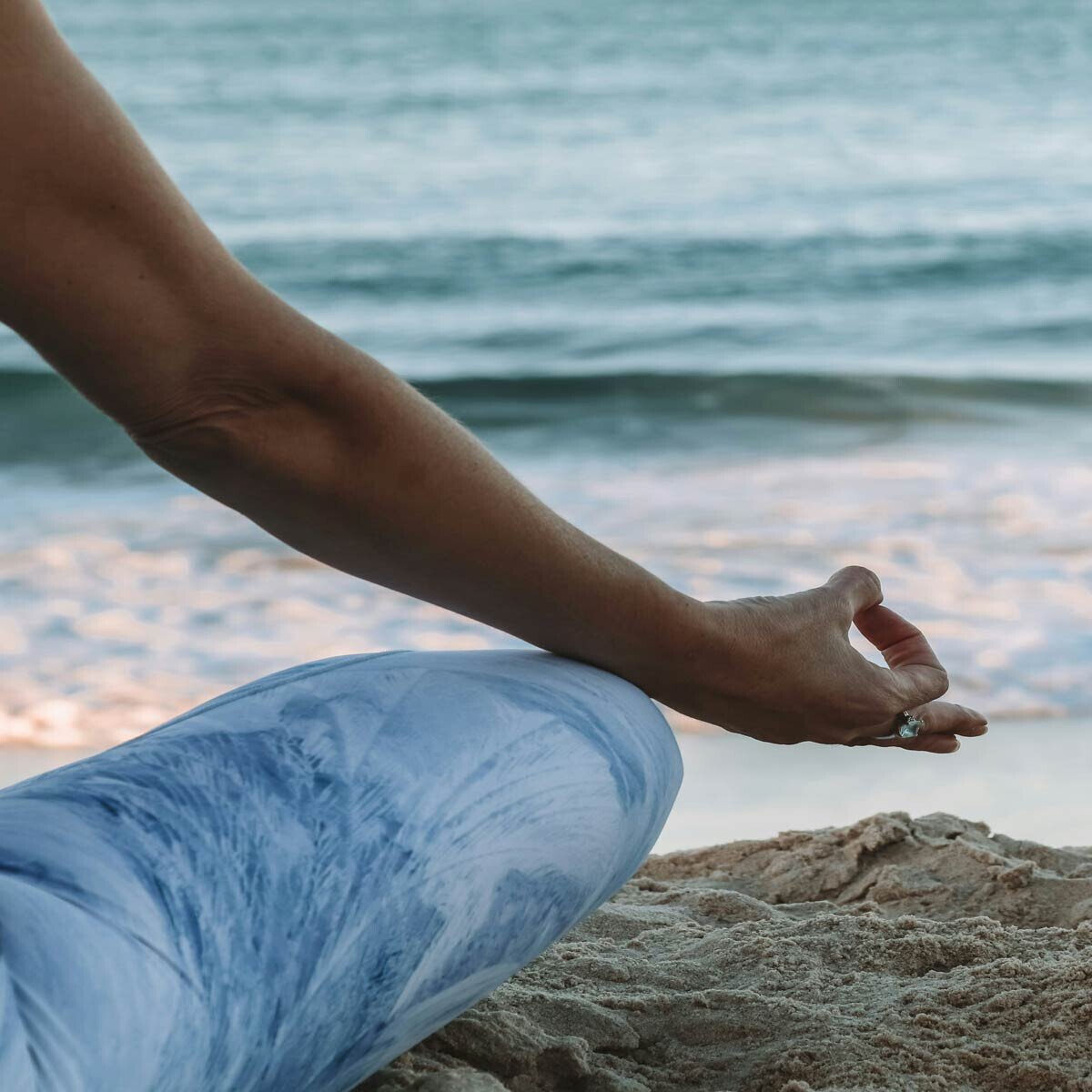 Hand in meditation pose during yoga on the beach by the sea.