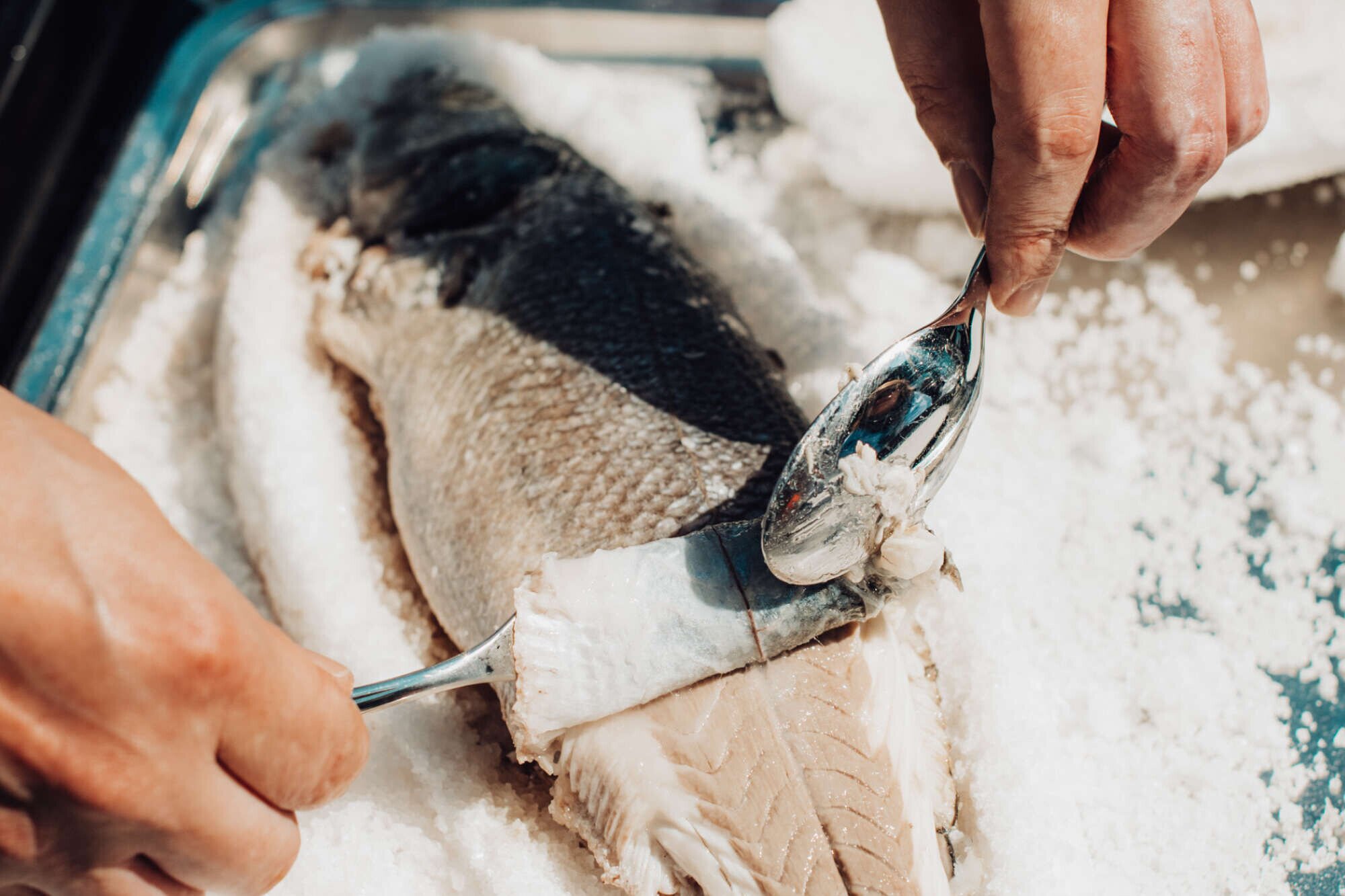 Chef preparing a salt-crusted fish in the kitchen of Hotel De Blanke Top.